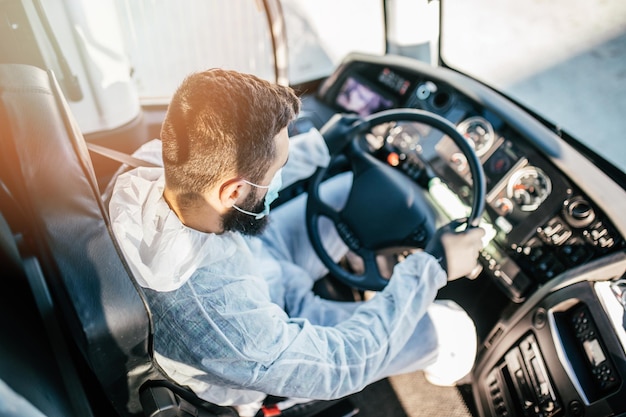 Kierowca zawodowy prowadzący autobus w odzieży ochronnej jako profilaktyka Covid - 19, koronawiry.