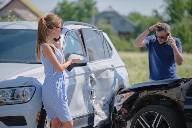 Kierowcy rozbitych pojazdów rozmawiają przez telefon komórkowy wołając o pomoc w wypadku samochodowym na ulicy. Koncepcja bezpieczeństwa ruchu drogowego i ubezpieczenia