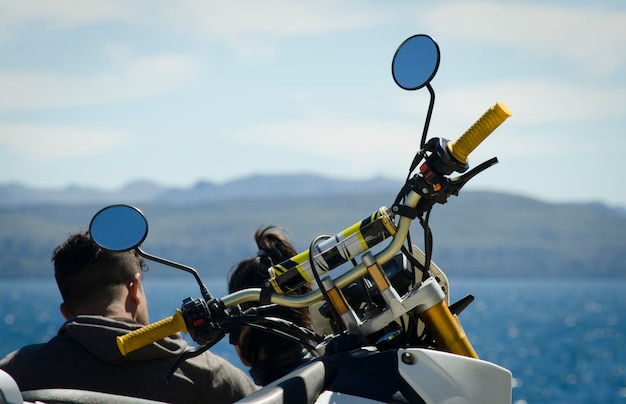 Kierownica motocykla na górskim wybrzeżu, rowerzyści odpoczywają.