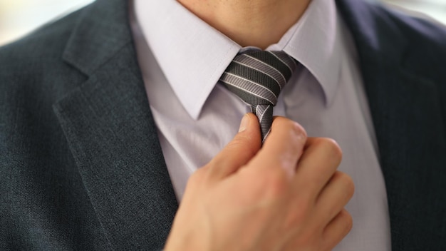 Kierownik biznesmena w garniturze prostujący krawat na koszuli w biurze zbliżenie