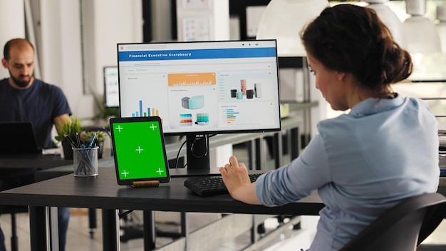 Kierownik używa zielonego ekranu na tabletie w biurze coworkingowym, prezentując izolowany układ copyspace na nowoczesnym gadżecie Kobieta biznesu używająca pulpitu PC i ekranu chromakey na biurku
