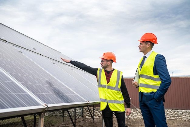 Kierownik w specjalnym ubraniu rozmawia z pracownikiem w specjalnym ubraniu kosztem montażu paneli ekonomicznych Koncepcja zielonej energii elektrycznej