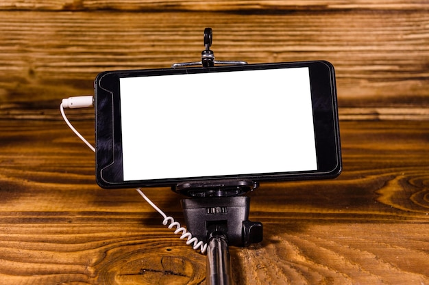 Kijek do selfie z nowoczesnym smartfonem na rustykalnym drewnianym stole