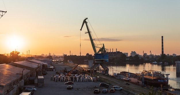 Kijów, Ukraina - 30 maja 2018: Przemysłowa dzielnica Kijowa w dzielnicy Podil. Dniepr i port rzeczny. Widok z mostu wantowego Rybalsky wieczorem podczas zachodu słońca