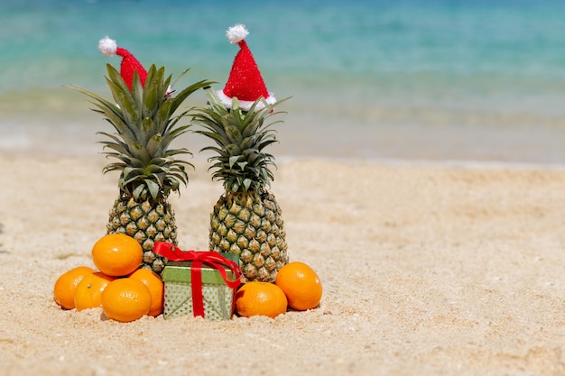 Kilka Ananasów W Santa Red Hat Na Plaży.