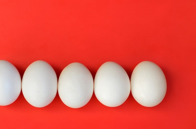 Kilka białych jaj na jasnym czerwonym tle
