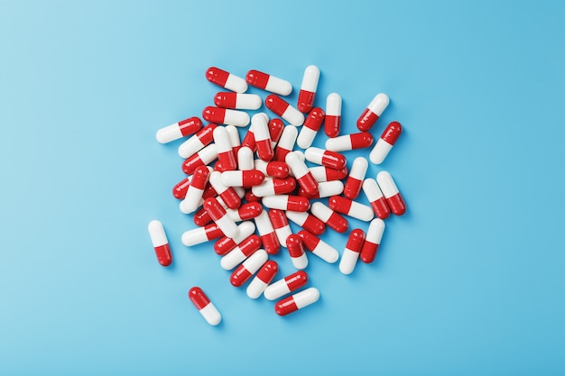 Kilka czerwonych i białych tabletek na niebieskim tle.