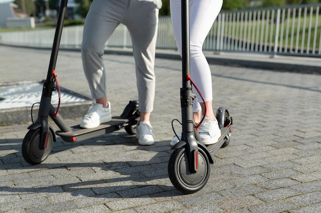 Kilka kobiet i mężczyzn spaceruje po parku i stoi w pobliżu skuterów elektrycznych