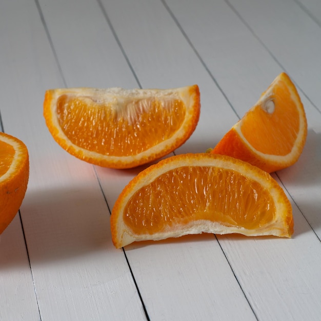 Kilka plasterków pomarańczy leży na białym stole.