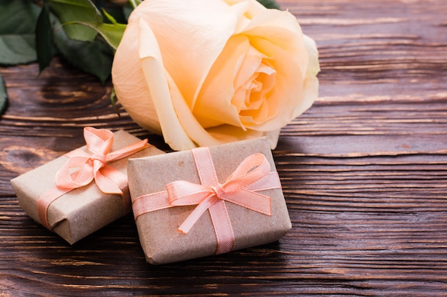 Kilka zapakowanych prezentów i świeża róża na drewnianym stole