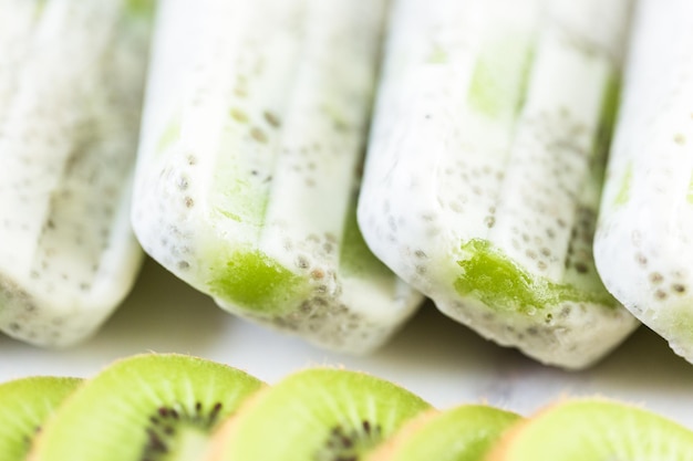 Kiwi kokosowe chia popsicles na białej marmurowej płycie.