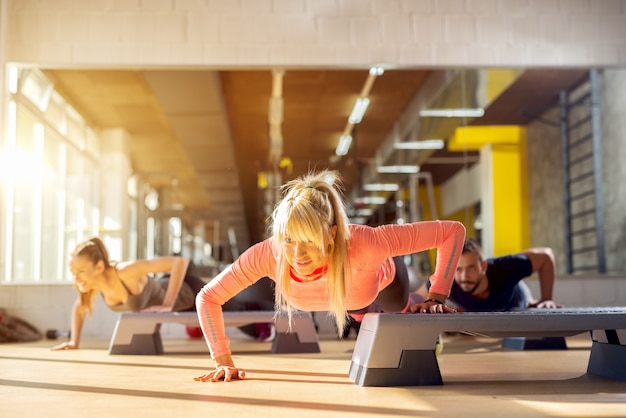 Klasa fitnes. Grupa młodych ludzi pracujących na siłowni