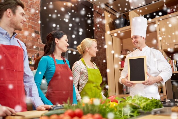Klasa Gotowania, Koncepcja Kulinarna, Jedzenie I Ludzie - Szczęśliwi Przyjaciele I Szef Kuchni Z Pustą Tablicą Kredową Menu W Kuchni Nad Efektem śniegu