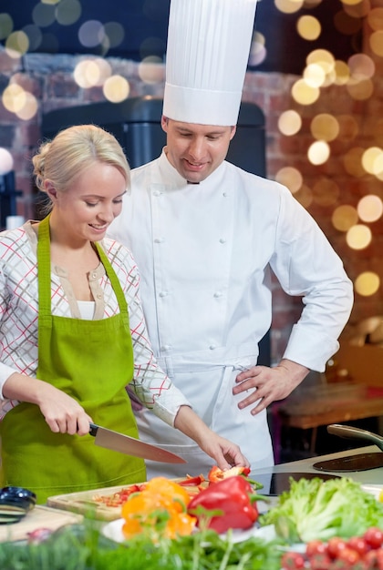 Zdjęcie klasa gotowania kulinarna jedzenie i ludzie koncepcja szczęśliwy szef kuchni mężczyzna z kobietą gotowanie w kuchni