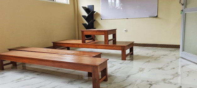 Klasa z brązowymi drewnianymi biurkami z białą tablicą w środku