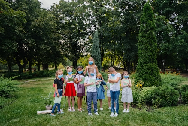 Klasa zamaskowanych dzieci w wieku szkolnym bierze udział w treningu na świeżym powietrzu podczas epidemii