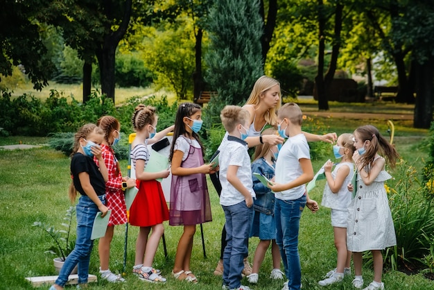 Klasa zamaskowanych dzieci w wieku szkolnym jest zaangażowana w trening na świeżym powietrzu podczas epidemii. Powrót do szkoły, nauka podczas pandemii.