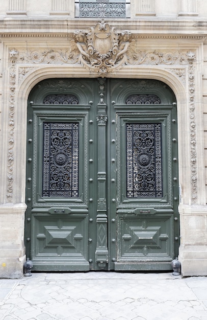 Klasyczna architektura wejście z drzwiami pomalowanymi na zielono i złotymi tabliczkami na panelach drzwiowych Fasada domu w Paryżu we Francji