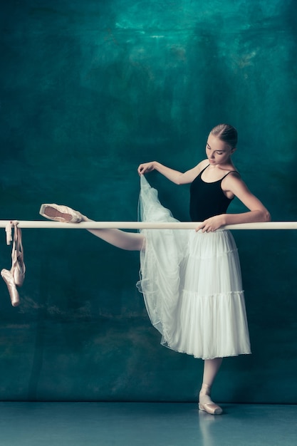 Klasyczna tancerka baletowa w białej spódniczce baletnicy pozuje na baletu na tle studia