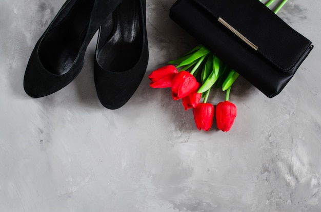 Zdjęcie klasyczne czarne damskie buty, mała torebka i czerwone tulipany.
