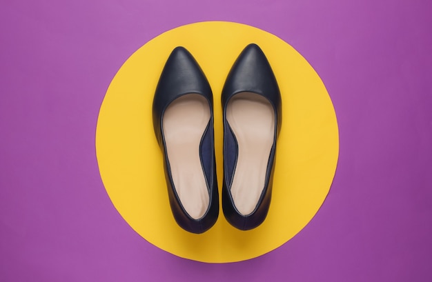 Klasyczne damskie buty na obcasie na fioletowym papierze z żółtym kółkiem pośrodku