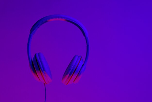 Klasyczne słuchawki przewodowe z gradientowym fioletowym, różowym neonowym światłem. Retro style.Retro fala. Lata 80. Minimalistyczna koncepcja muzyki.
