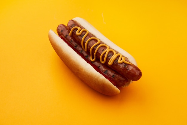 Klasyczny hot dog z podwójnym ketchupem i musztardą na pomarańczowym tle menu dla restauracji