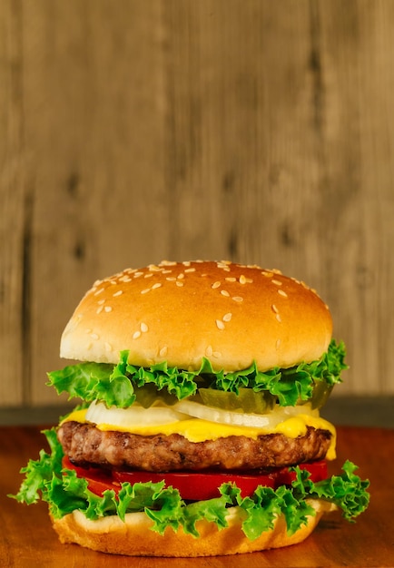 Klasyczny luksusowy cheeseburger z sałatą, cebulą, pomidorem i piklami na bułce sezamowej makro z s