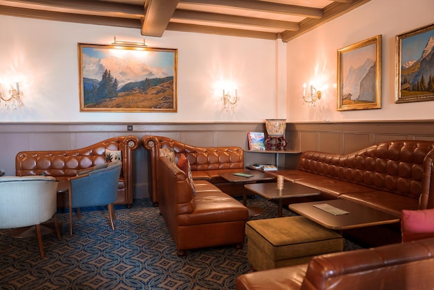 Klasyczny salon z skórzanymi kanapami, niebieskimi krzesłami i vintage dekoracją w przytulnej przestrzeni
