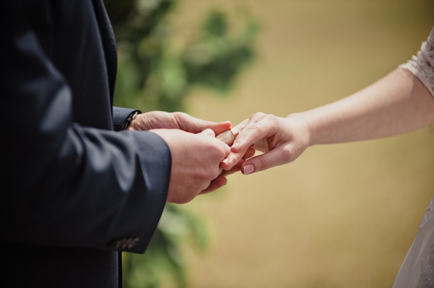 Klasyczny ślub na wiosnę. Ceremonia i łuk ze świeżymi kwiatami. Narzeczeni wymieniają pierścienie.