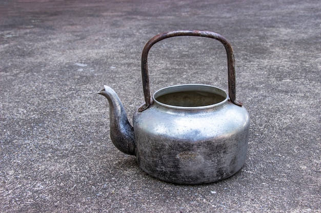 Klasyczny stary czajnik przy stawiającym na betonowym tle.