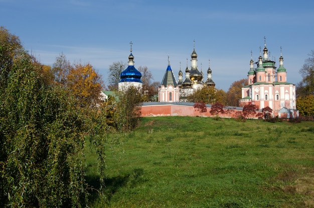 Klasztor Święto-Troicki na tle jesiennych drzew w Gustyny. Obwód Czernihowa. Ukraina. Poziomy strzał na zewnątrz.