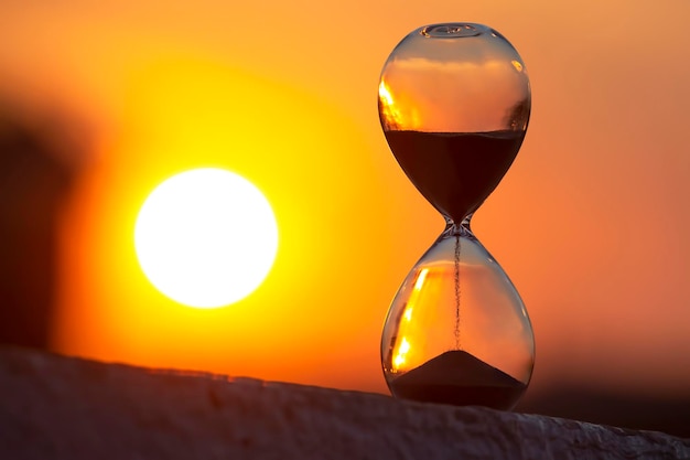 Zdjęcie klepsydra liczy czas na tle zachodzącego słońca