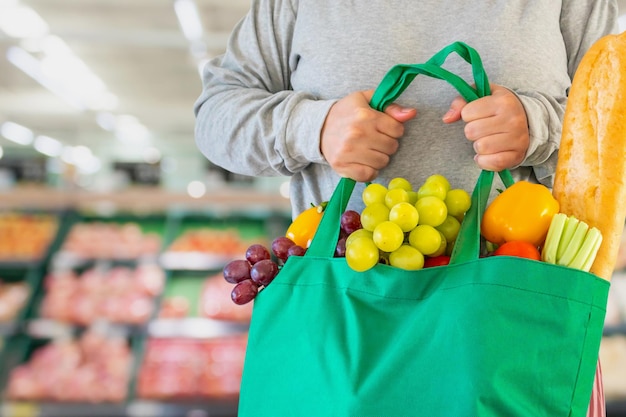 Klient Trzyma Torbę Na Zakupy Z Owocami I Warzywami Na Tle Rozmycia Supermarketu