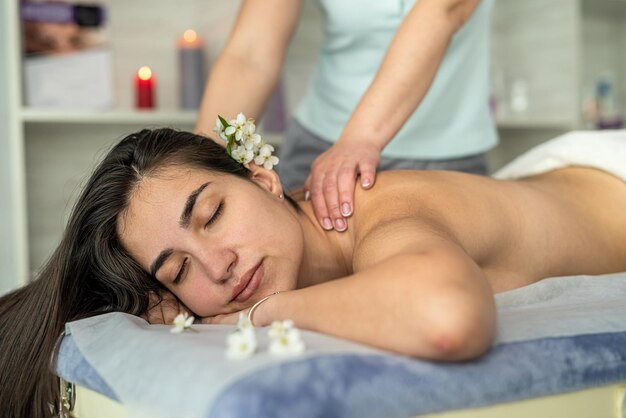 Klientka leżąca na stole poddająca się masażowi odmłodzenia pleców w salonie spa Zdrowy styl życia relaksacyjnego