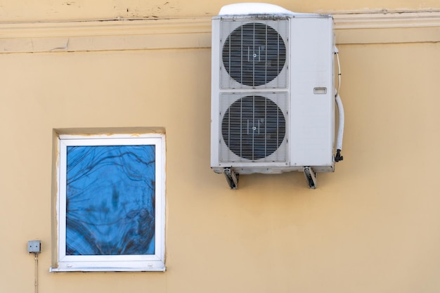 Klimatyzator zewnętrzny montowany na ścianie budynku mieszkalnego przy oknie Montaż napraw i konserwacji instalacji klimatyzacyjnych w lokalach mieszkalnych