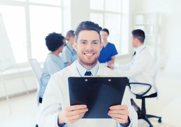 Klinika, zawód, ludzie i medycyna koncepcja - szczęśliwy lekarz z tabletem komputerowym nad grupą lekarzy spotykających się w szpitalu