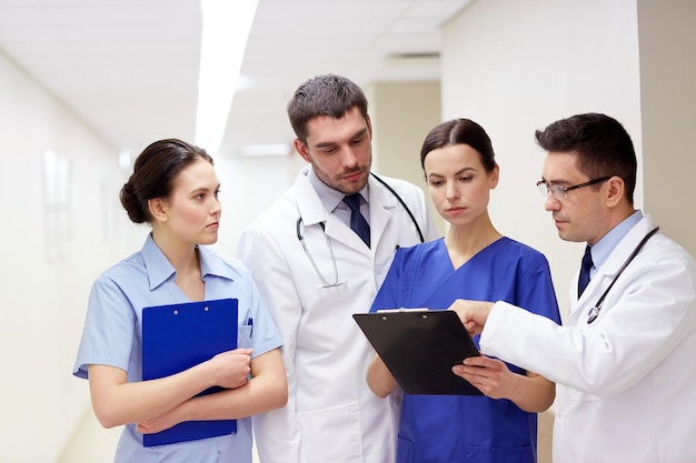 klinika, zawód, ludzie, opieka zdrowotna i koncepcja medycyny - grupa lekarzy lub lekarzy ze schowkiem na szpitalnym korytarzu