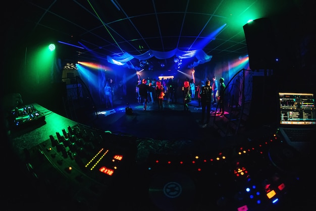 Klub nocny z tańczącymi ludźmi na parkiecie, biesiadnikami na imprezie i zarząd muzyczny DJ-a