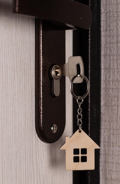 Klucz z kluczykiem w kształcie domu w dziurze klucza drzwi