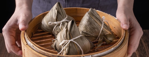 Kluski ryżowe zongzi Dragon Boat Festival Kilka chińskich tradycyjnych gotowanych potraw w parowcu na drewnianym stole na czarnym tle z bliska miejsce