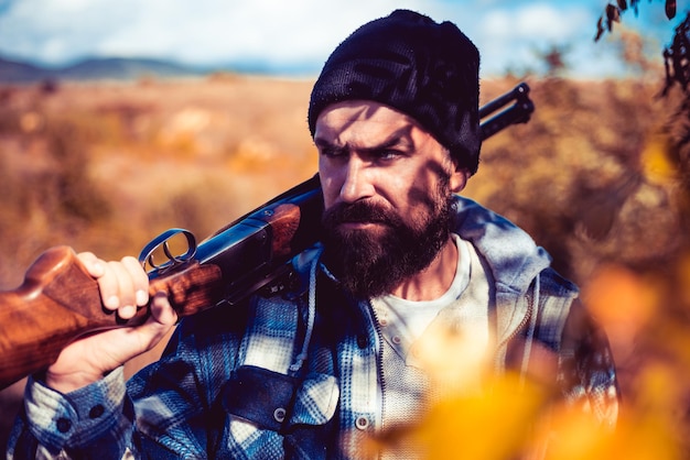 Zdjęcie kłusownik w lesie. brodaty mężczyzna myśliwy trzyma broń i spacery w lesie. licencje myśliwskie. hunter z pistoletem na polowanie.