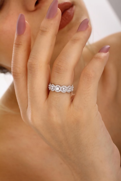 Kobieca dłoń z pierścionkiem z napisem „diament”.
