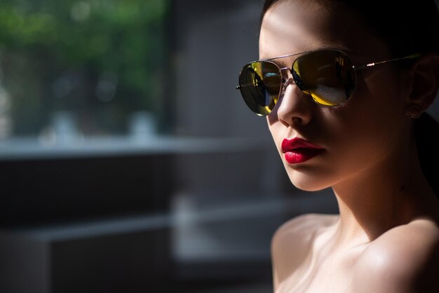 Kobieca modelka pozuje z okularami przeciwsłonecznymi seksowny zbliżenie portret pięknej uroczej młodej atr