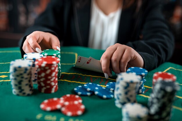 Kobieca ręka bierze żetony ze stosu przy okrągłym stole pokerowym ryzykowne zakłady w pokera