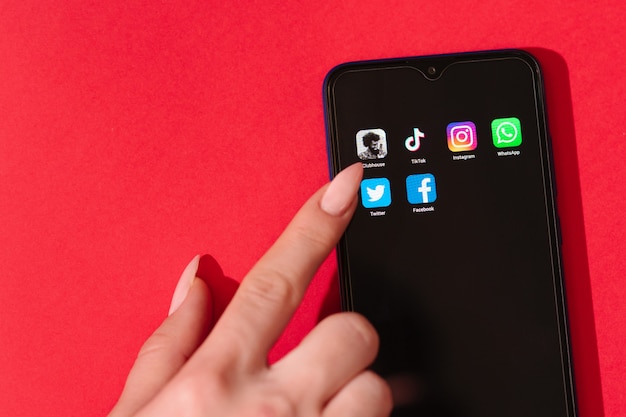 kobiecą ręką dotyka ekranu smartfona z popularnymi aplikacjami społecznościowymi