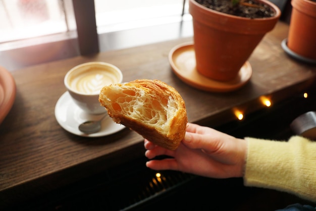 Kobieca Ręka Trzymająca Filiżankę świeżo Ugryzionego Rogalika Cappuccino Na Tle