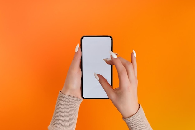 Kobieca ręka trzymająca i dotykająca smartfona mobilnego z białym ekranem izolowany na szablonie Orange Photo dla dowolnych obrazów na wyświetlaczu telefonu komórkowego Układ z łatwo usuwalnym tłem monitora telefonu
