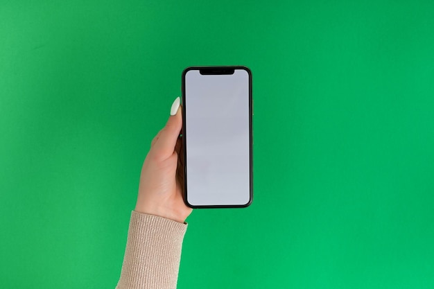 Kobieca ręka trzymająca i dotykająca smartfona z białym ekranem izolowany na zielonym szablonie zdjęć dla dowolnych obrazów na wyświetlaczu telefonu komórkowego Układ z łatwo usuwalnym tłem monitora telefonu