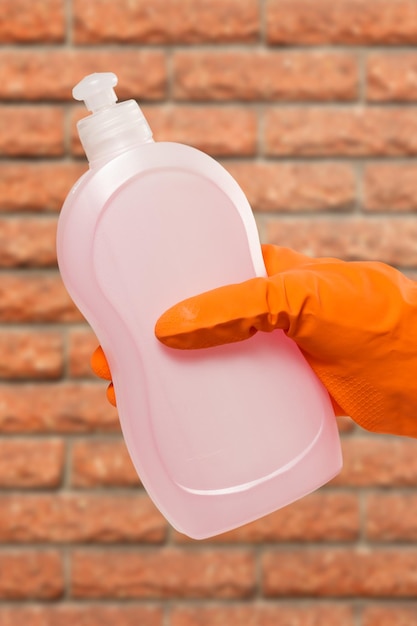 Zdjęcie kobieca ręka w ochronnej rękawiczce z butelką płynu czyszczącego